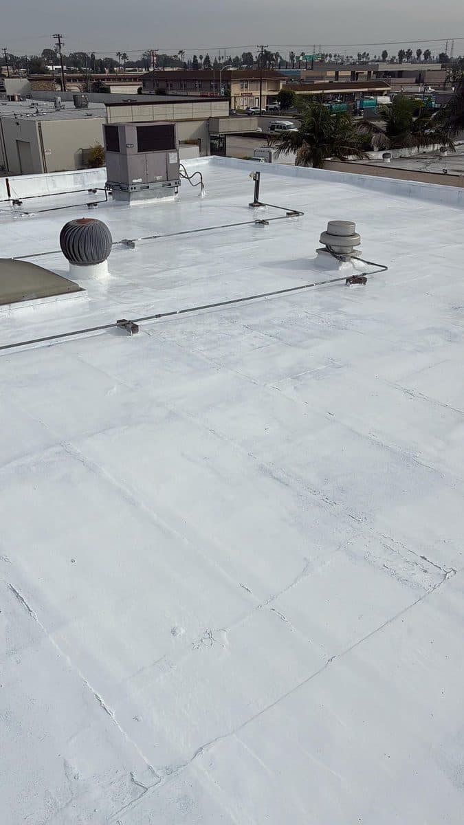 White flat roof surface with turbine vents, a rooftop unit and an electrical cable