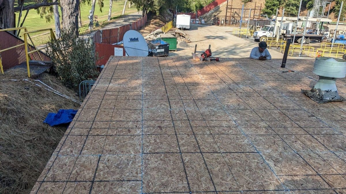 Wood roof deck with a crew member at the far edge and rooftop vents