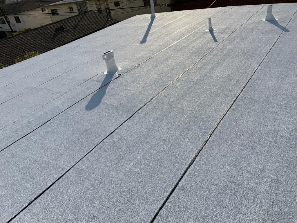 White flat roof with seam lines and a pipe vent