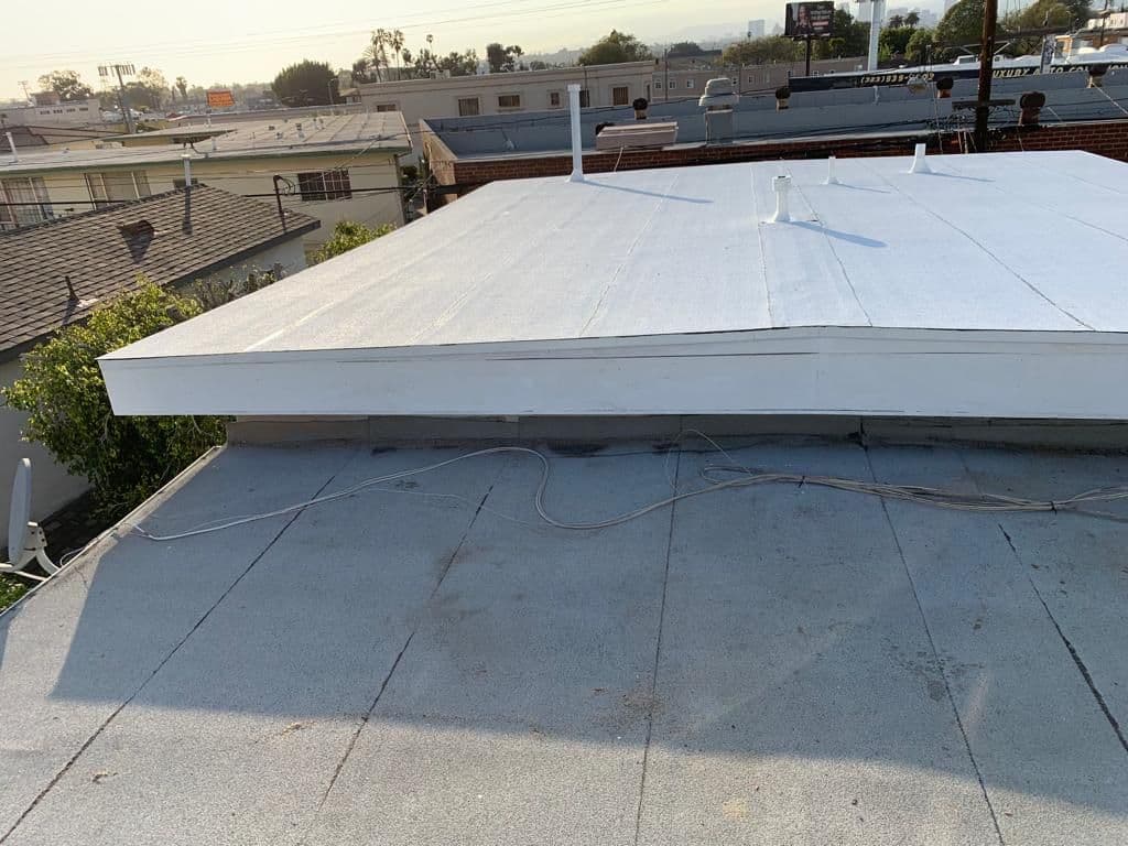 Flat roof with a raised white section above a gray roof surface