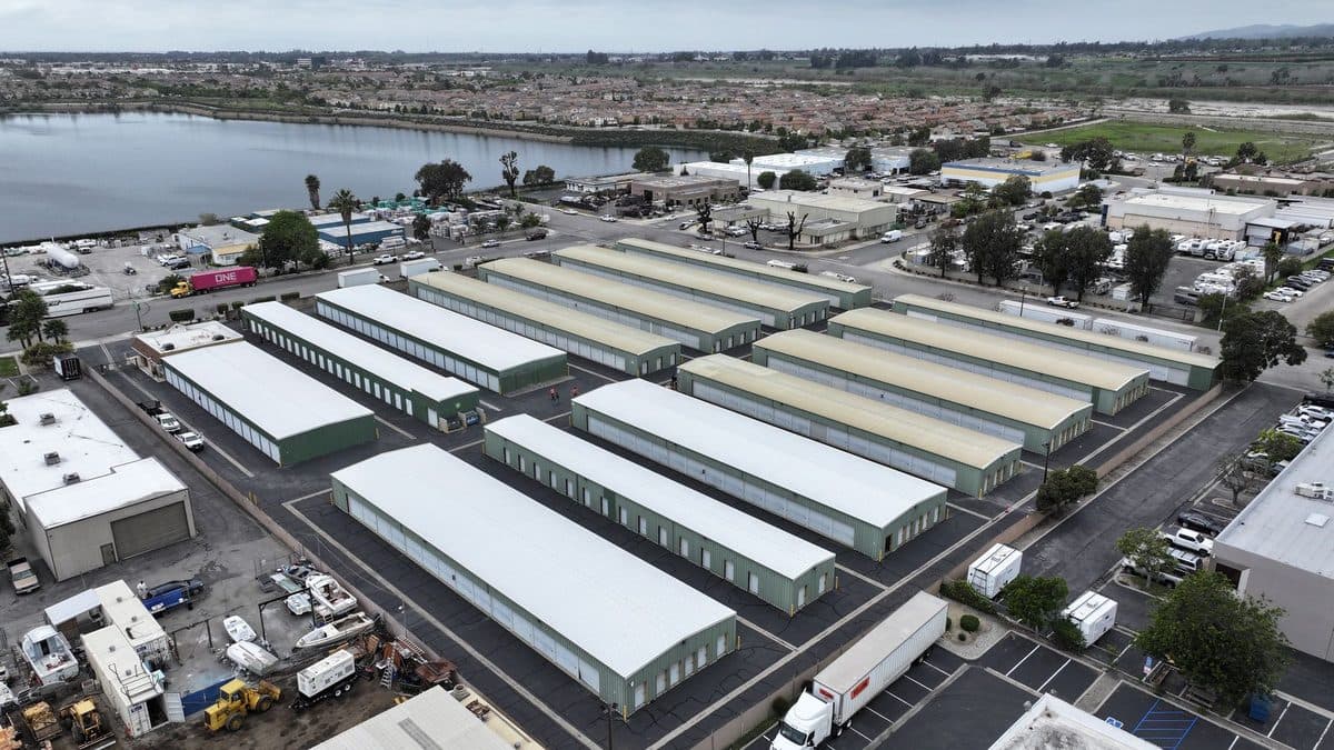 Aerial view of rows of long white-roofed storage buildings beside a waterway