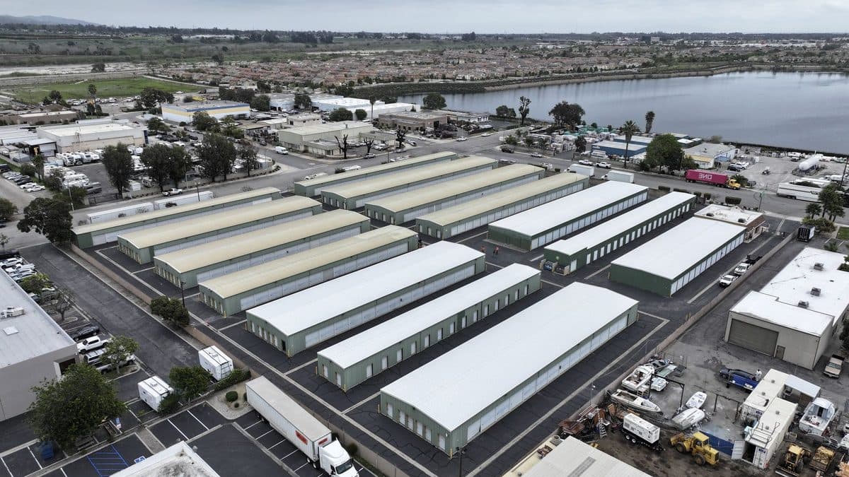 Aerial view of rows of long storage building roofs beside a waterway