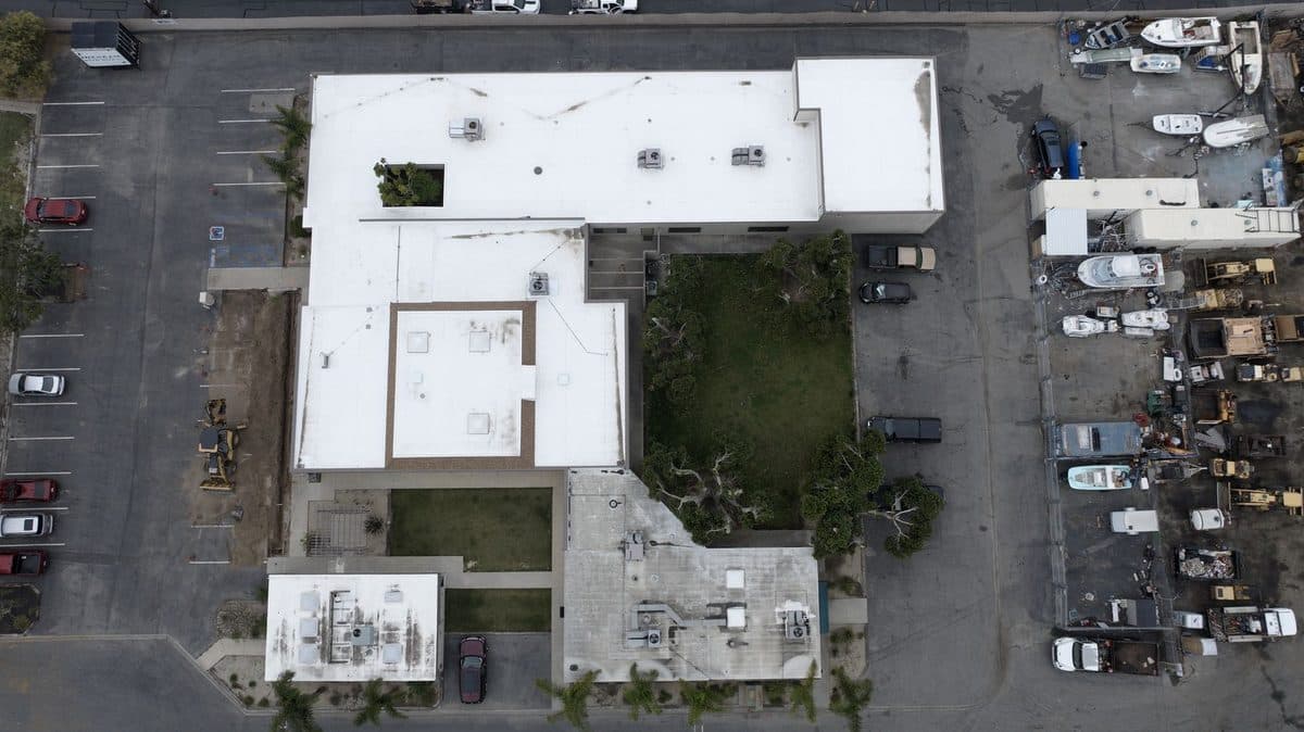 Top-down aerial view of a commercial building complex with white flat roofs and a courtyard
