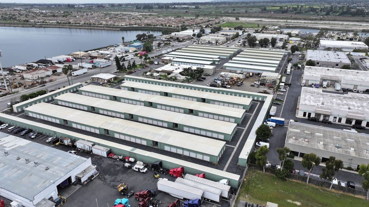 Aerial view of rows of long storage building roofs beside a lake