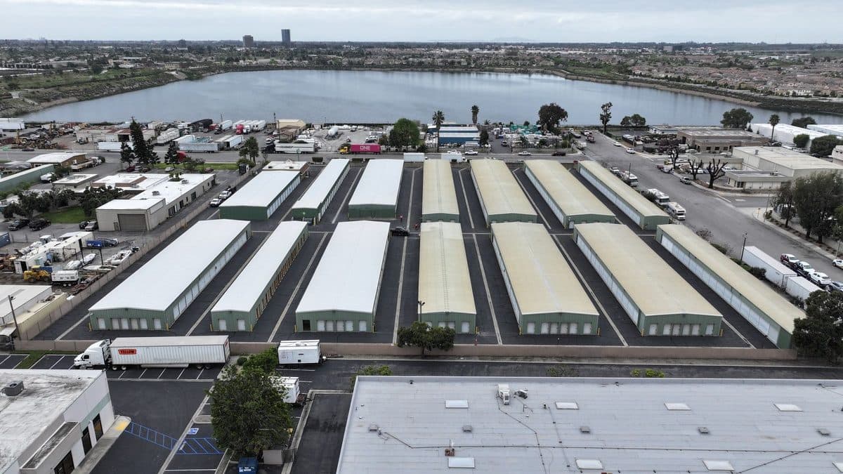 Aerial view of rows of long storage building roofs with a lake in the distance