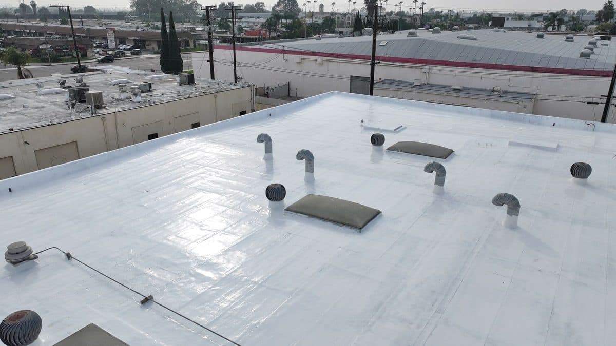 Glossy white flat roof with turbine vents and skylights