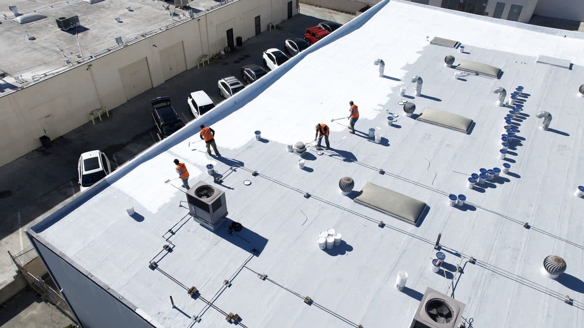 Aerial view of crew members working on a large commercial flat roof with rooftop units
