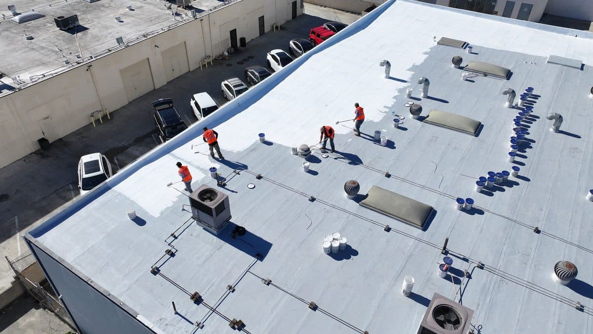 Aerial view of crew members working on a commercial flat roof with rooftop units