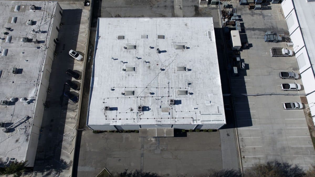 Aerial view of a white flat-roofed commercial building beside a parking lot