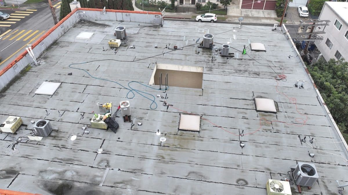 Aerial view of a gray flat roof with rooftop units and skylights