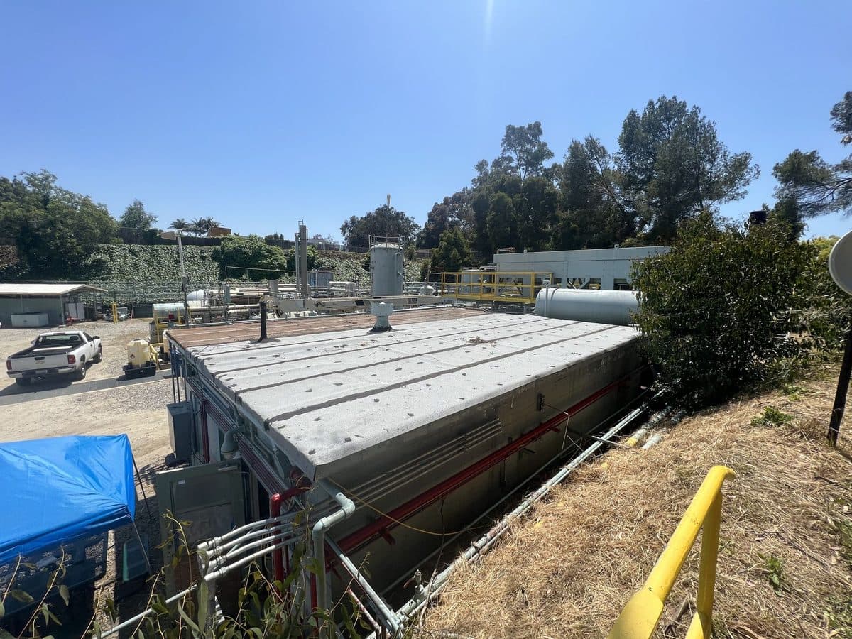 Long flat roof section beside a hillside at an industrial site