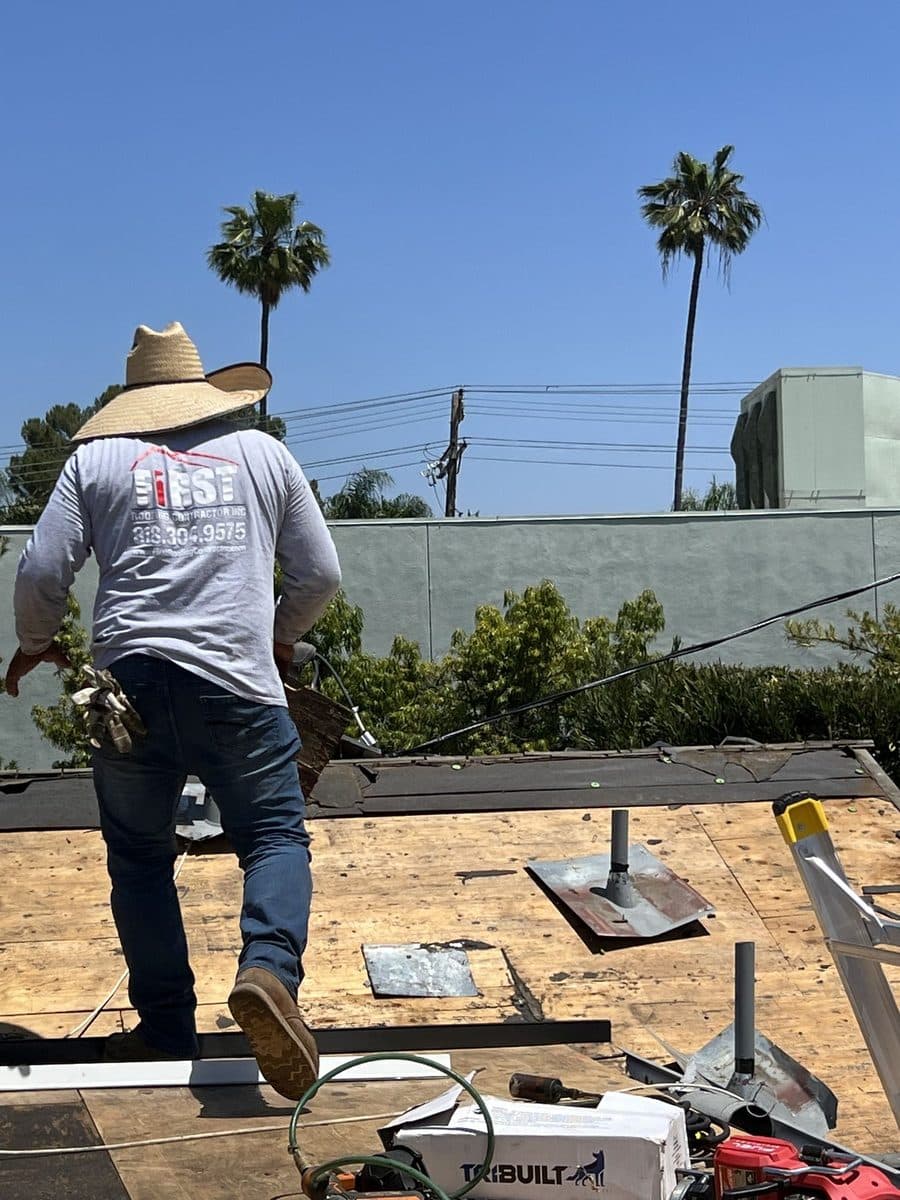 Crew member working on a roof deck with vent flashings and tools