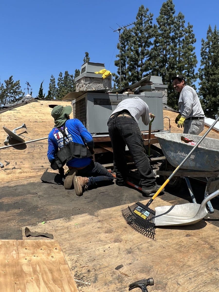 Crew members working on a plywood roof deck near rooftop equipment
