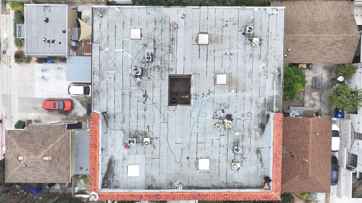 Top-down aerial view of a commercial flat roof with rooftop units and a clay tile border