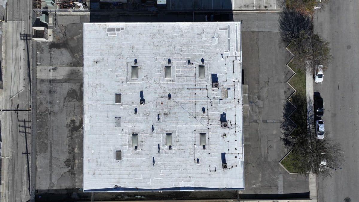 Top-down aerial view of a white commercial flat roof with skylights and rooftop units