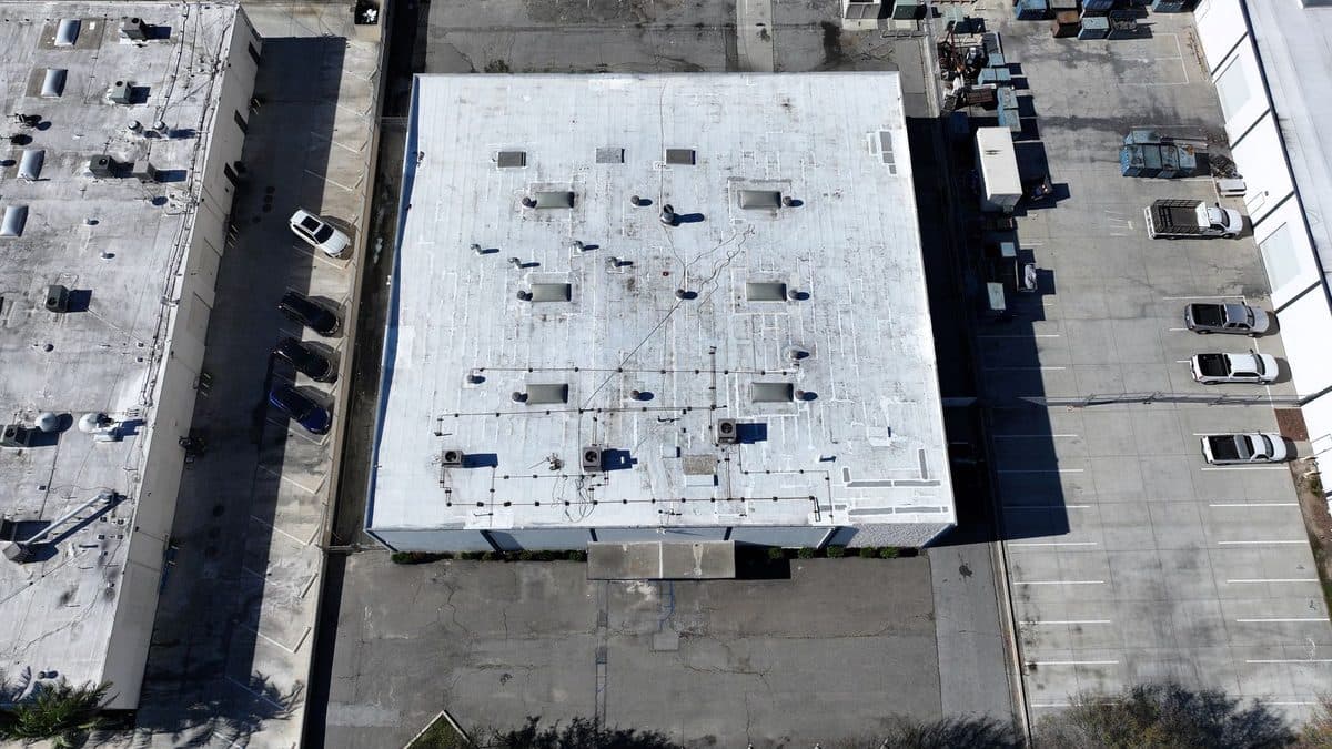 Angled aerial view of a white commercial flat roof with skylights and rooftop units