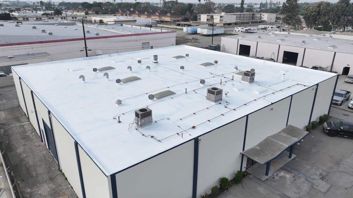 Aerial view of a white flat roof on a commercial building with rooftop units and skylights