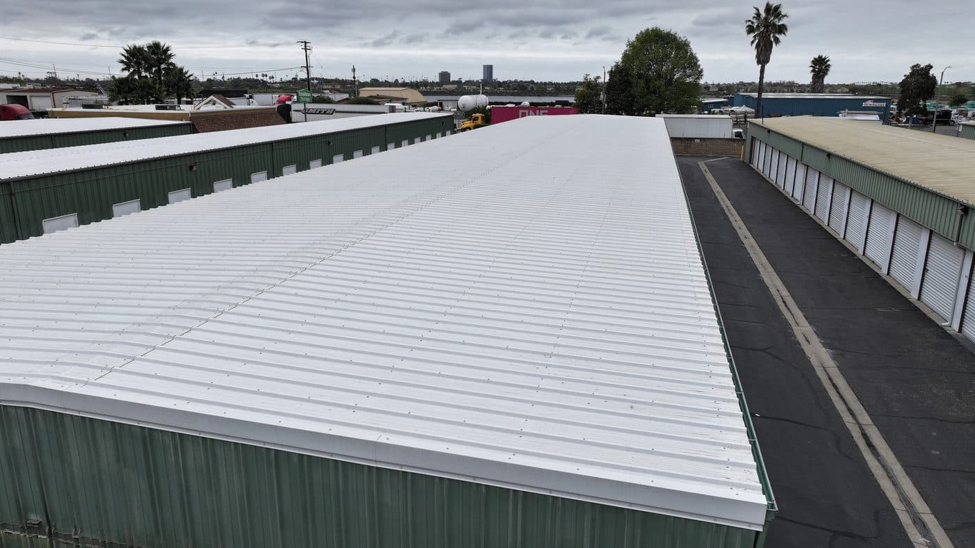 Long white commercial building roof with green walls, photographed from above