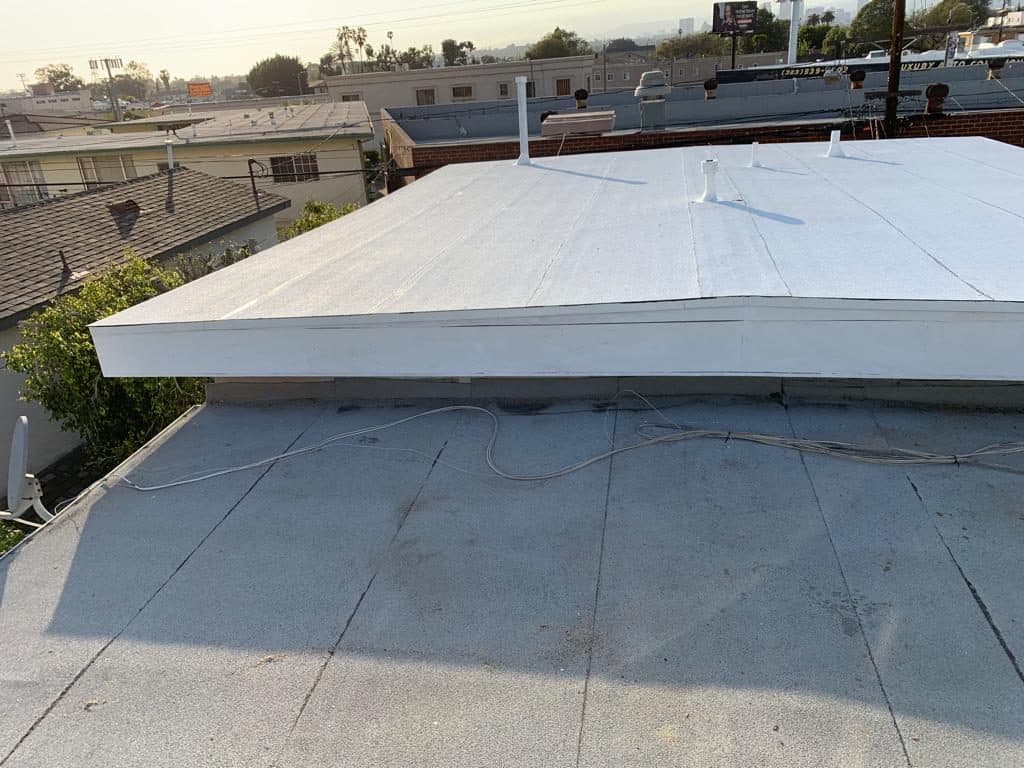 Commercial flat roof with a raised white section, photographed from the roof surface