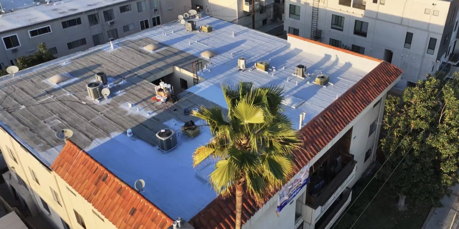 Aerial view of a flat commercial building roof partially coated with a silicone roof coating