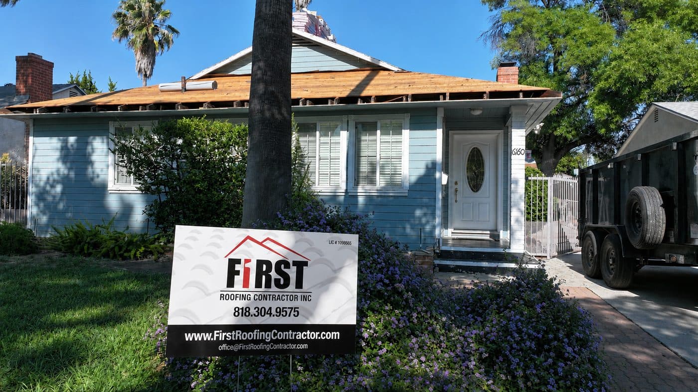 First Roofing Contractor crew re-roofing a home in Los Angeles, with company yard sign in front
