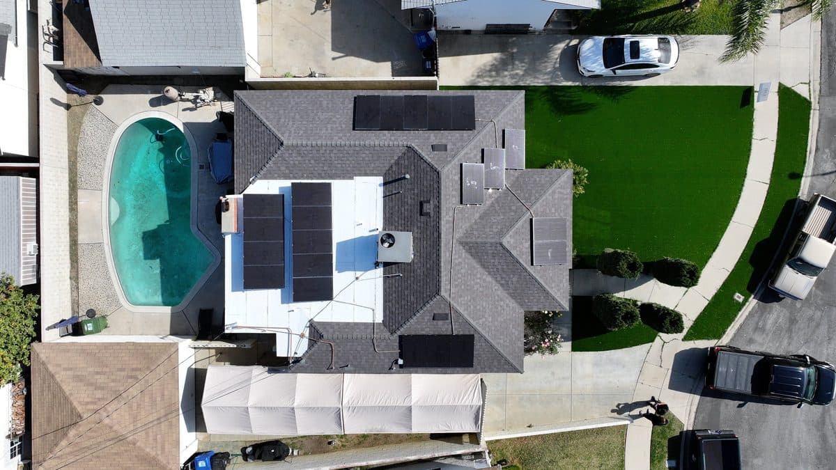 Aerial view of a completed shingle roof with solar panels