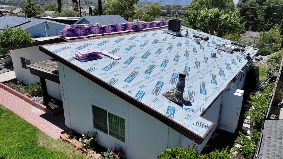 Aerial view of underlayment installed with shingle bundles staged on the roof