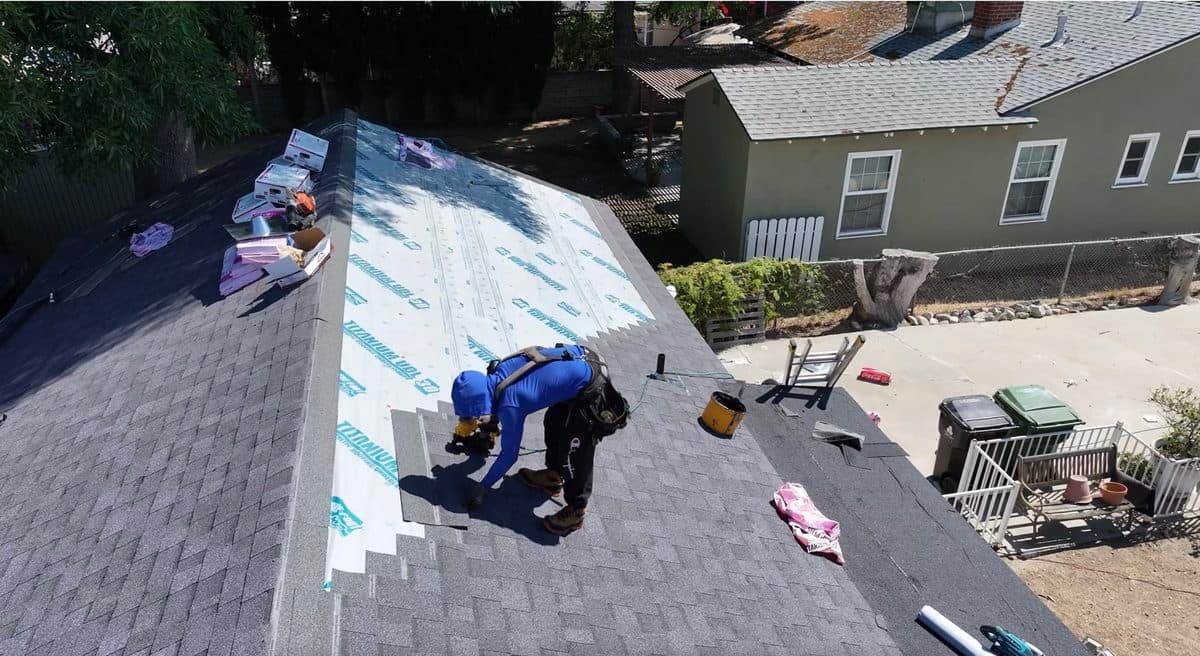 Aerial view of a roofing crew tearing off an old flat roof section