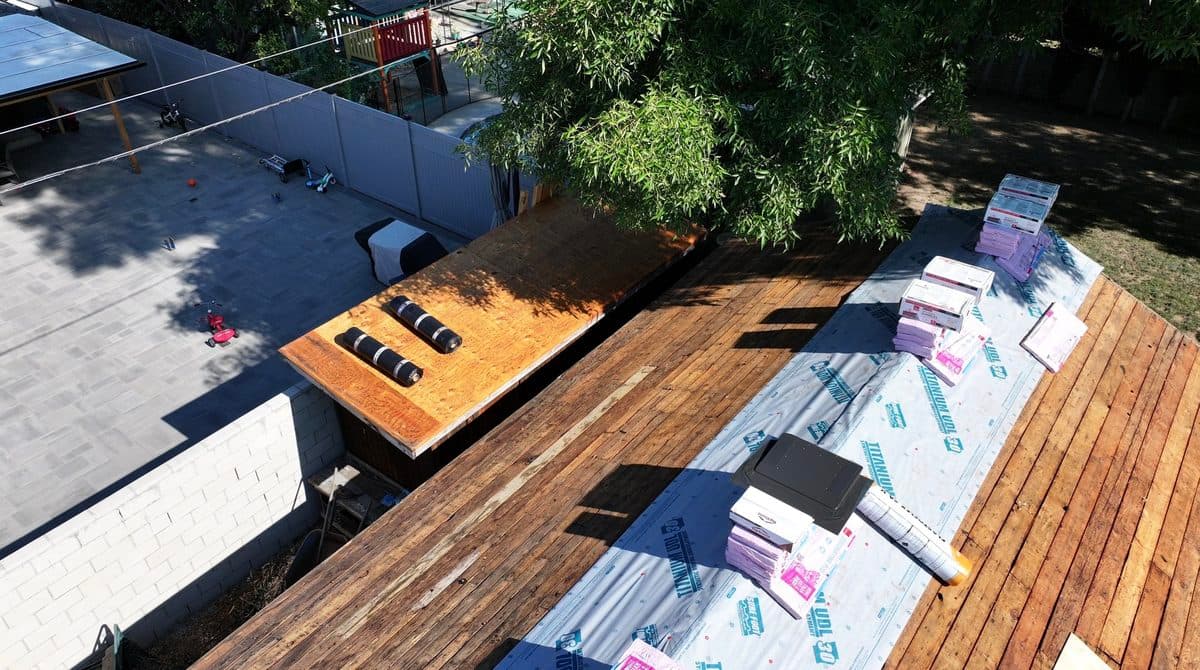 Aerial view of synthetic underlayment and shingle bundles staged on a roof