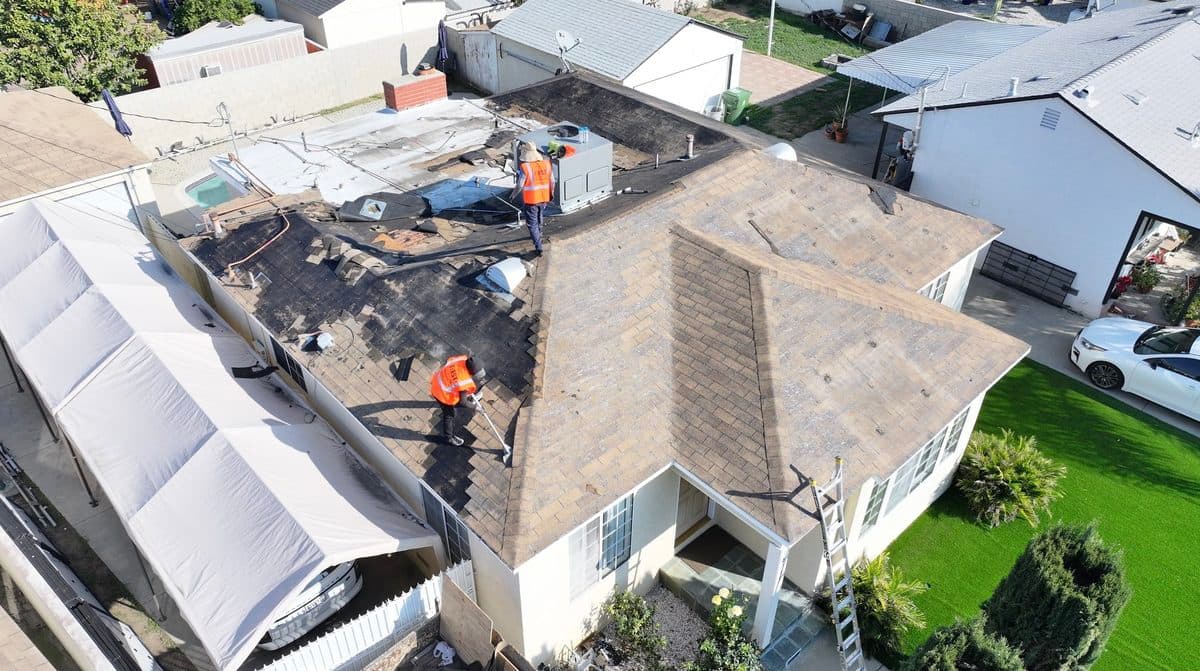 Roofing crew wearing First Roofing Contractor safety vests during a tear-off