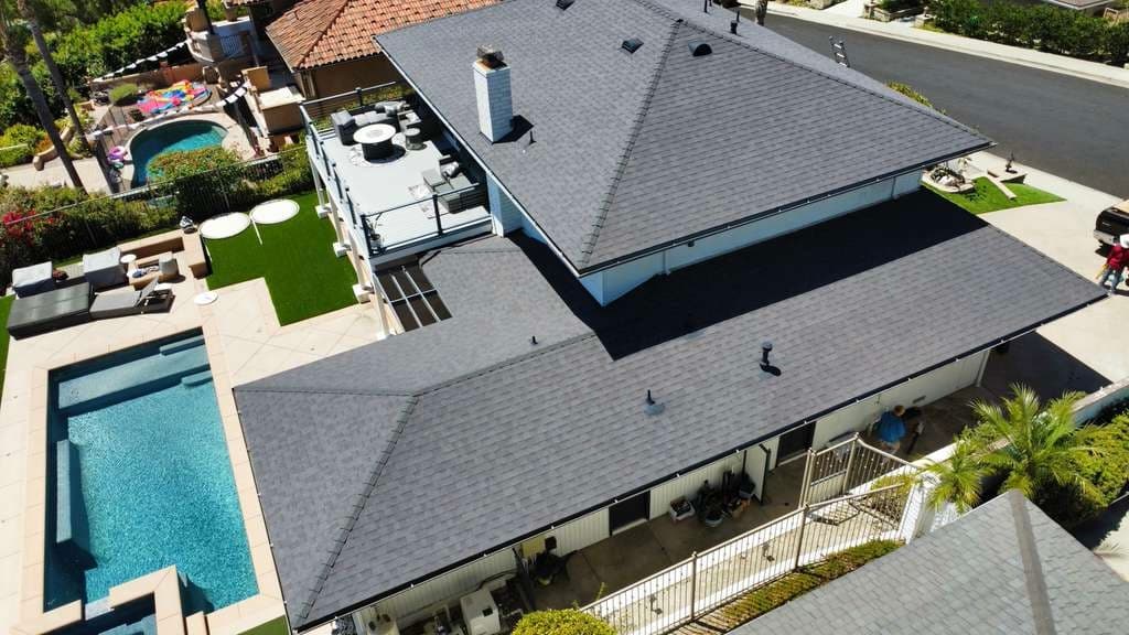 Aerial view of a completed residential shingle roof with pool