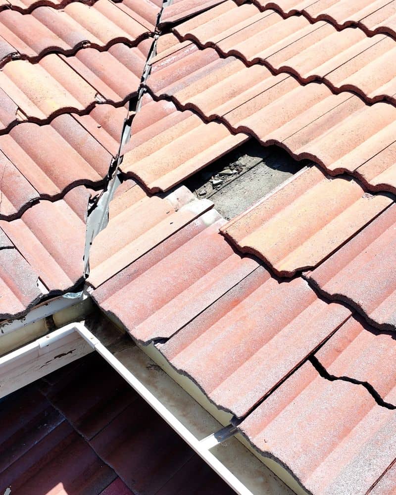 Close-up of cracked and broken roof tiles along a roof edge