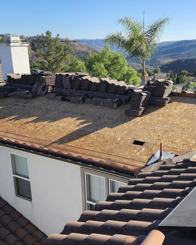 Roof stripped to the deck with tile staged in stacks during a re-tile