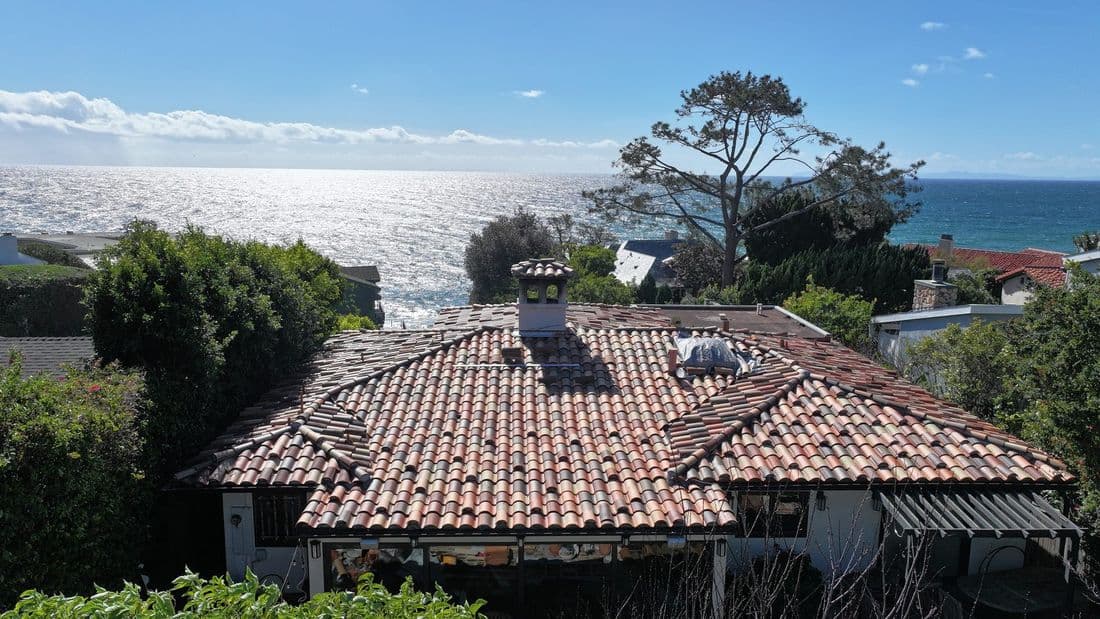 Completed terracotta tile roof on a coastal home with the ocean behind it