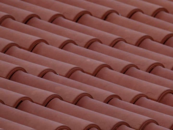 Clay barrel roof tiles in red terracotta, close-up